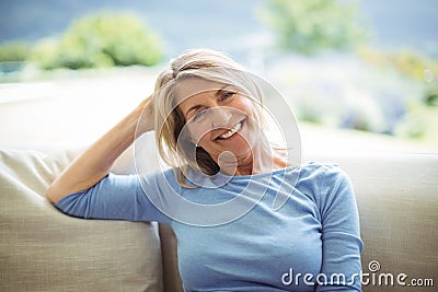 Portrait of smiling senior woman sitting on sofa in living room Stock Photo