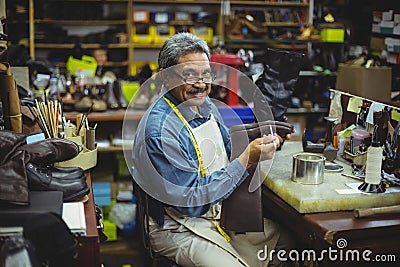 Portrait of smiling shoemaker applying glue on shoe Stock Photo