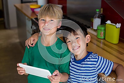Portrait of smiling siblings using digital tablet in kitchen Stock Photo