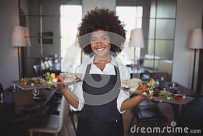 Portrait of smiling waitress holding food tray Stock Photo