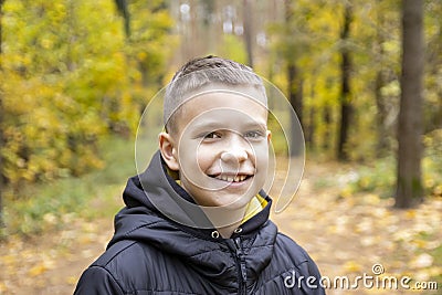 Portrait of a smiling 10-year-old boy in a jacket against the background of an autumn yellow forest. Concept: autumn holidays, goi Stock Photo