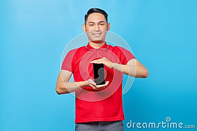 Portrait of smiling young asian man showing blank screen mobile phone isolated on bluebackground Stock Photo