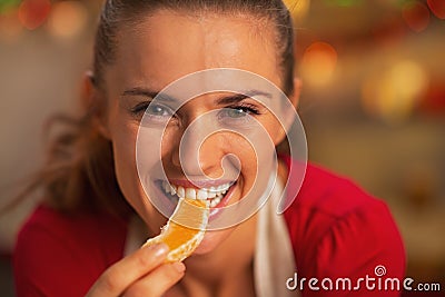 Portrait of smiling young housewife eating orange Stock Photo