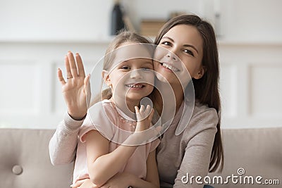 Happy mom and little daughter look at camera waving Stock Photo