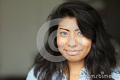 Portrait of a Smiling young Spanish woman. She is happy isolated on gray Stock Photo