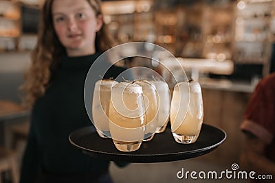 Smiling bar waitress holding a tray of drinks Stock Photo