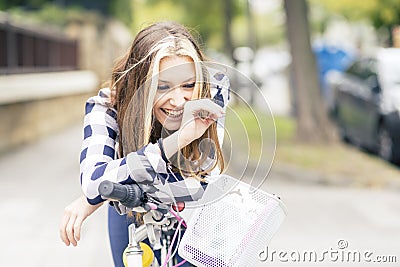Portrait of smiling young woman with bicycle in the street. Stock Photo