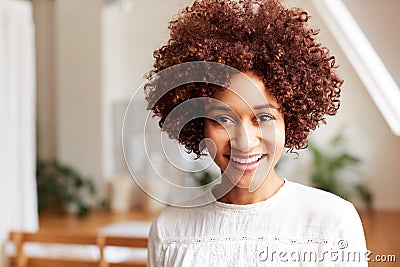 Portrait Of Smiling Young Woman In Loft Apartment Stock Photo