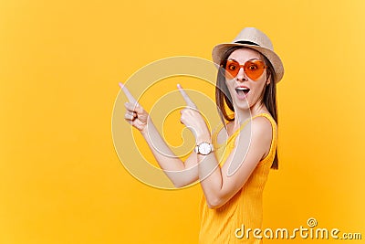 Portrait of smiling young woman in straw summer hat, orange glasses pointing index fingers aside copy space isolated on Stock Photo