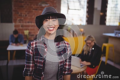 Smiling young woman wearing hat standing at coffee shop Stock Photo