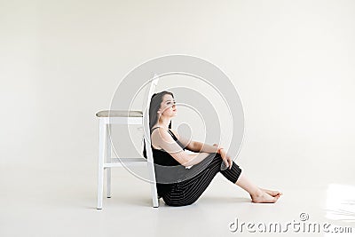 Portrait of smilling girl sitting with chair, on a white background Stock Photo