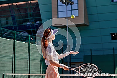 portrait of sporty lady tennis player with racket, raising throwing ball up Stock Photo