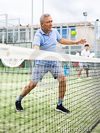 Sporty senior man playing padel on open tennis court Stock Photo