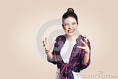 Portrait of stressed and annoyed young casual styled caucasian woman with hair bun holding hands in mad furious gesture, screaming Stock Photo