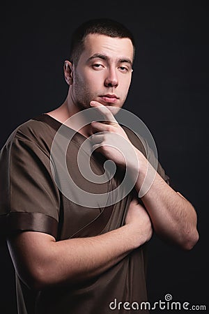 Portrait of a strong and large male masseur in special clothes with a finger at the temple reads your chin and knows all Stock Photo