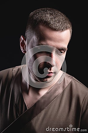 Portrait of a strong and large male masseur in special clothes with a finger at the temple reads your chin and knows all Stock Photo