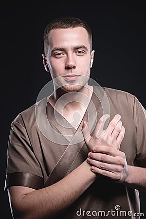 Portrait of a strong and large male masseur in special clothes with a finger at the temple reads your chin and knows all Stock Photo