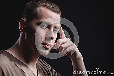 Portrait of a strong and large male masseur in special clothes with a finger at the temple reads your thoughts and knows Stock Photo