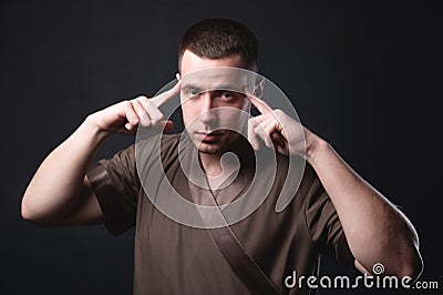 Portrait of a strong and large male masseur in special clothes with a finger at the temple reads your thoughts and knows Stock Photo