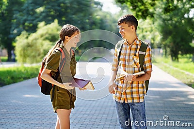 Portrait of students in a city park, teenage schoolchildren a boy and a girl are standing on the path and discussing lessons, Stock Photo