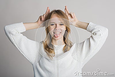 Portrait of a stylish and cheerful girl on a white background in the studio who shows funny grimaces. Stock Photo