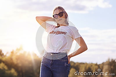 Portrait of stylish female youngster in casual clothes and shades, enjoys summer time, poses against clear sky, has trendy hairsty Stock Photo