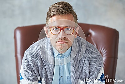 Portrait of a stylish intelligent man with glasses stares into the camera, good view, small unshaven, charismatic, blue shirt, gra Stock Photo