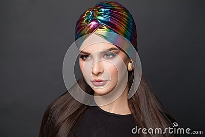 Portrait of stylish woman with long smooth straight hair and makeup in turban hat on black background Stock Photo