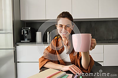 Portrait of stylish young woman, student shares her cup of coffee, gives you mug, smiling and looking happy Stock Photo