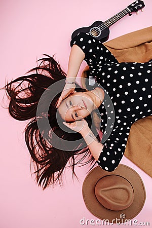 Portrait of a subtly smiling young woman lying on the floor, over pink Stock Photo