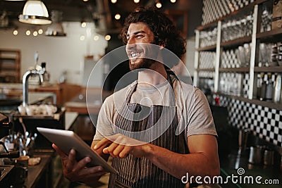 Portrait of successful young caucasian cafe owner standing behind counter using digital tablet Stock Photo