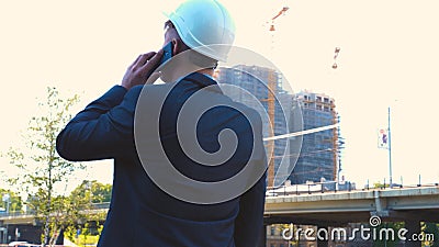 Portrait of a successful young handsome engineer, architect, builder, businessman, wearing a white helmet, in a suit, holding a pr Stock Photo