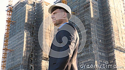 Portrait of a successful young handsome engineer, architect, builder, businessman, wearing a white helmet, in a suit, holding a pr Stock Photo