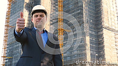 Portrait of a successful young handsome engineer, architect, builder, businessman, wearing a white helmet, in a suit, holding a pr Stock Photo