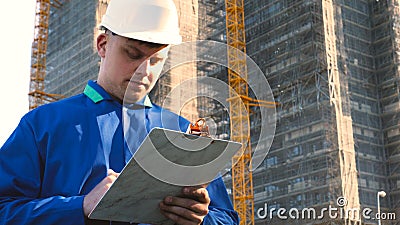 Portrait of a successful young handsome engineer, architect, builder, businessman, wearing a white helmet, in a suit, holding a pr Stock Photo