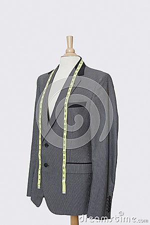 Suit on tailor`s dummy with measuring tape over gray background Stock Photo
