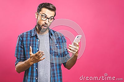 Portrait of a surprised casual man looking at mobile phone isolated over pink background Stock Photo