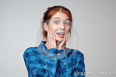 Portrait of surprised ginger female dressed casually in blue t-shirt, having bated breath. Stock Photo