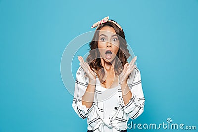 Portrait of surprised or shocked woman 20s wearing casual clothing raising up hands at face, isolated over blue background Stock Photo