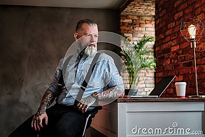 Senior businessman sitting at table with laptop in office Stock Photo