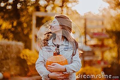 Portrait of teen girl with long hair posing with pumpkin at the open farm market place. Autumn background Stock Photo