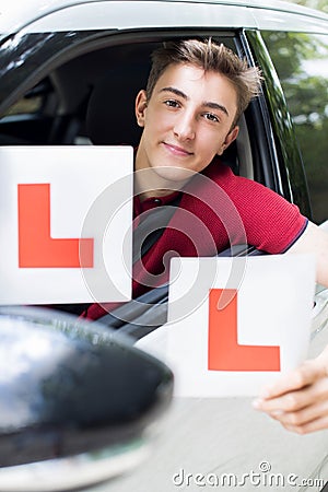 Portrait Of Teenage Boy Passing Driving Exam Holding Learner Plates Stock Photo