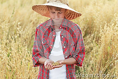 Portrait of teenage farmer boy is checking oat or Avena sativa seeds in cupped palms Stock Photo