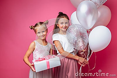 Portrait of a teenage girl on a pink background, with gifts, birthday concept, one gives another girl a gift Stock Photo