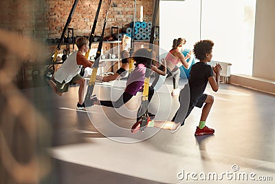 Portrait of teenage kids training using fitness straps in gym with female trainer. Sport, healthy lifestyle, physical Stock Photo