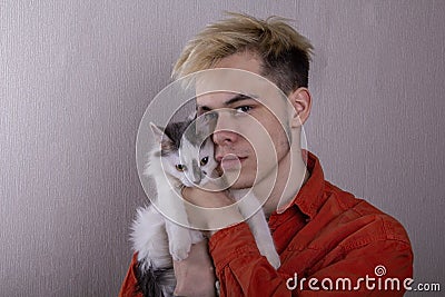 Portrait of a teenager holding a cat on a gray background. Concept: pets, caring for animals, love for our smaller brothers. Stock Photo