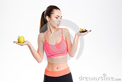 Portrait of tempted attractive fitness woman making food choice Stock Photo