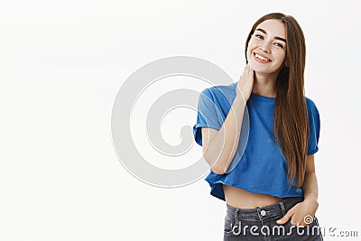 Portrait of tender and feminine cute female in cropped blue t-shirt touching neck shy and flirty tilting head and Stock Photo