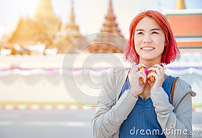 Portrait Thai Asian girl new generation young pop teen dyed red hair color shade smiling with Thailand temple background Stock Photo