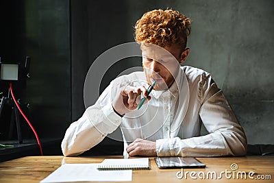 Portrait of thinking young readhead man in white shirt, sitting Stock Photo